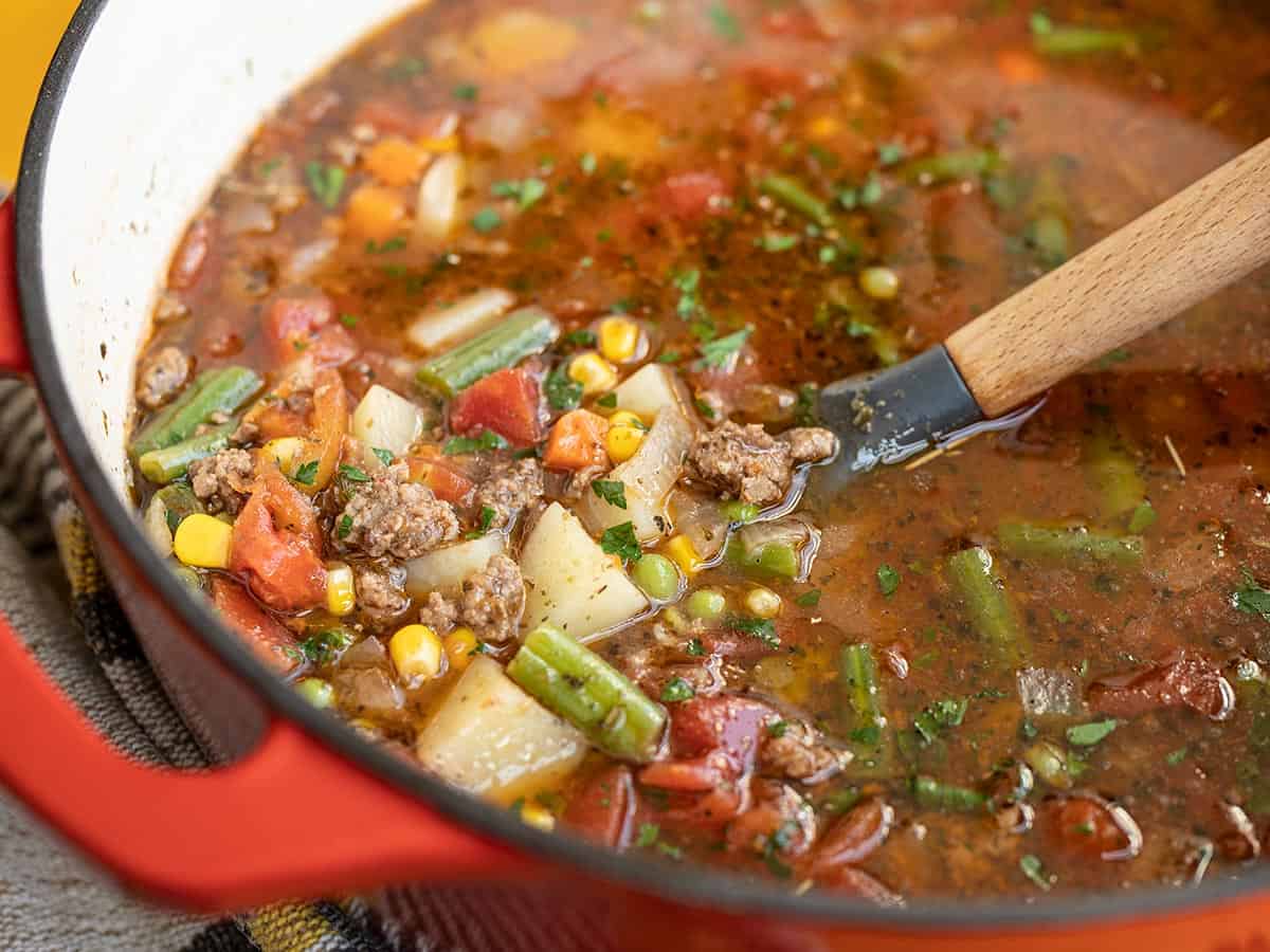 Side view of a the pot of Vegetable Beef Soup with a spoon.