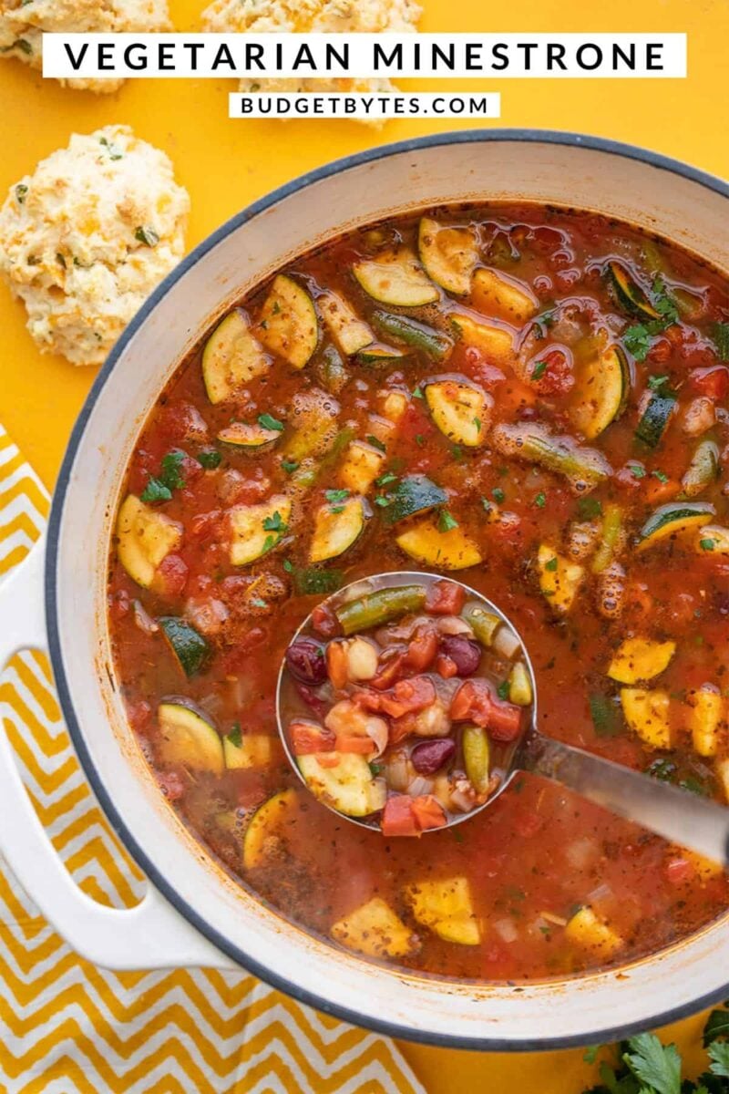 Overhead view of a pot of minestrone soup with a ladle, title text at the top