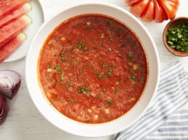 overhead view of watermelon gazpacho in a white bowl with minced fresh herbs.