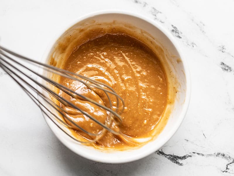 Peanut lime dressing being whisked in the bowl.